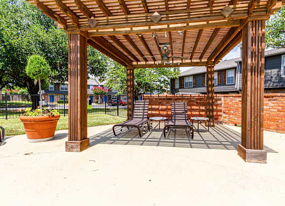 a wooden pergola with a table and chairs under it