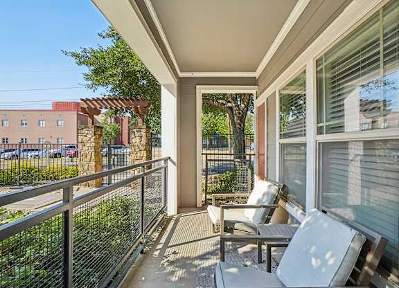 A patio with a table and chairs overlooks a parking lot.