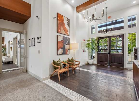A hallway with a brown wooden floor and a white wall with a framed picture of a woman.