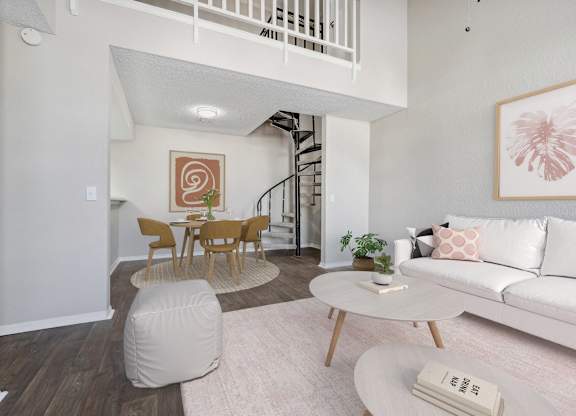 a living room with a white couch and a table and a spiral staircase