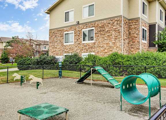 A playground with a green slide and a green table in the middle of the playground.