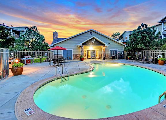 A swimming pool surrounded by a fence and a house in the background.