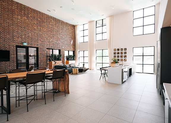 a large living room with a kitchen and dining area and tall windows