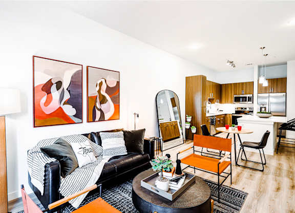 a living room with a couch and a table and a kitchen in the background