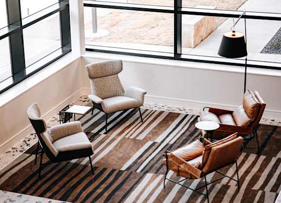 a living room with chairs and a rug