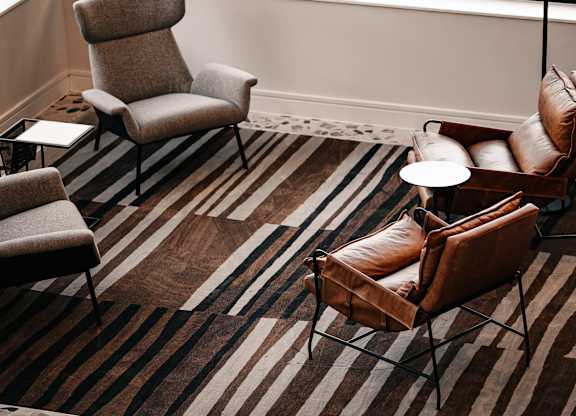 a living room with chairs and a rug and a large window