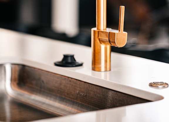 a close up of a gold faucet in a kitchen sink