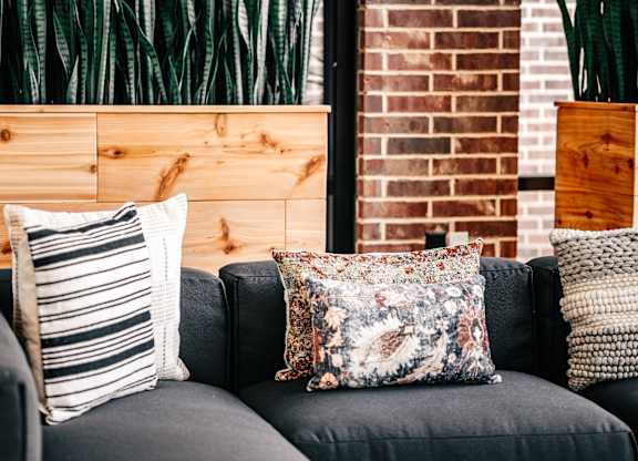 a couch with pillows in front of a brick wall