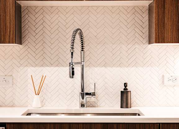 a kitchen with white tile and a sink and a faucet