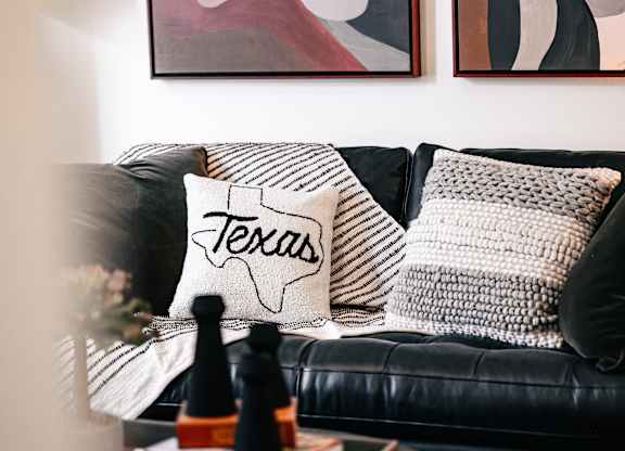a living room with a black couch and pillows on it