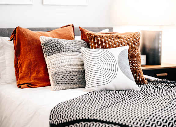 a bed with many pillows on it and a black and white blanket