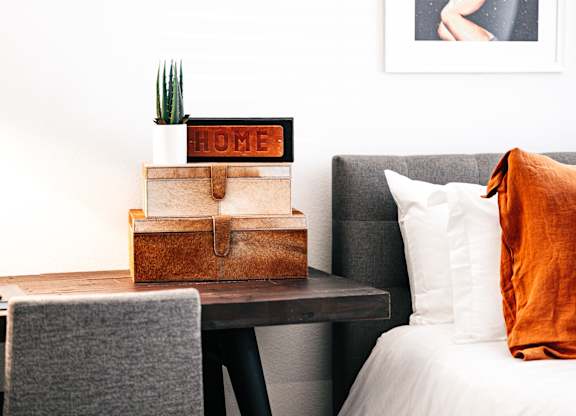 a bedroom with a bed and a table with a stack of boxes on it