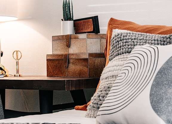 a bedroom with a bed with pillows and a desk with a cactus