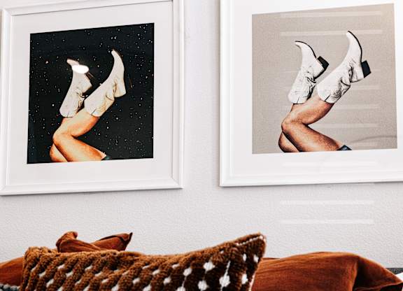 two pictures hanging on a wall next to a couch with pillows