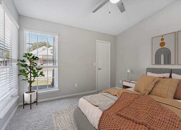 a bedroom with a bed and two windows and a ceiling fan