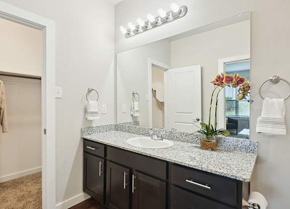 A bathroom with a vanity, mirror, and lights.