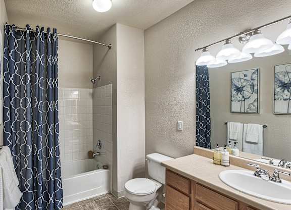 A bathroom with a white toilet, a white sink, and a blue shower curtain.