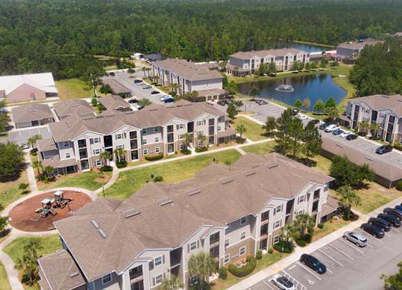 A bird's eye view of a residential complex with a pond and a playground.