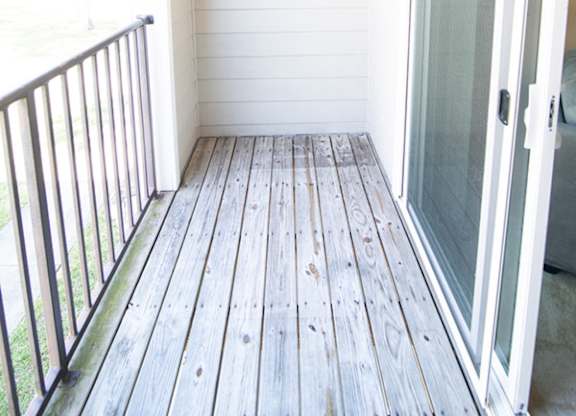 A white door is on the right side of a wooden deck.