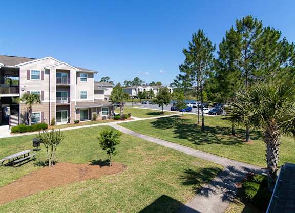 Apartment complex with a green lawn and trees.