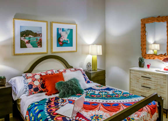 A bedroom with a bed, nightstand, and two framed pictures on the wall.