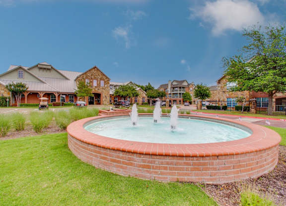 a fountain in the middle of a park in front of a house
