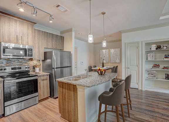 a kitchen with stainless steel appliances and a island with chairs