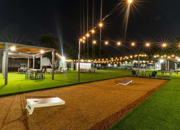 a night view of a yard with tables and chairs and lights