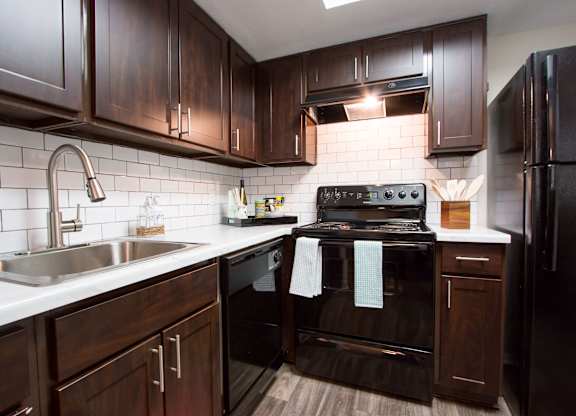 A kitchen with dark wood cabinets and black appliances.