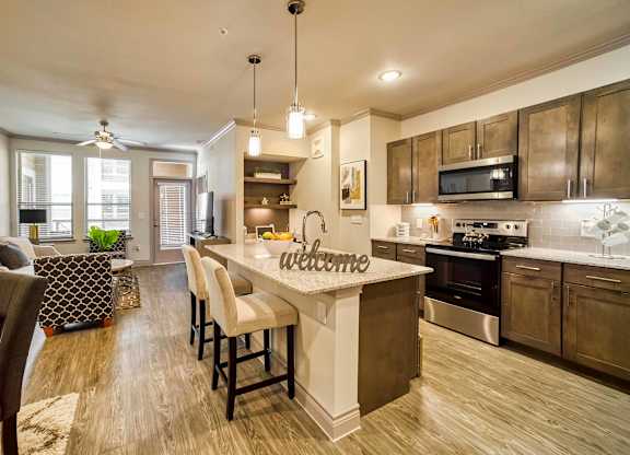 A modern kitchen with a large island and a welcome sign.