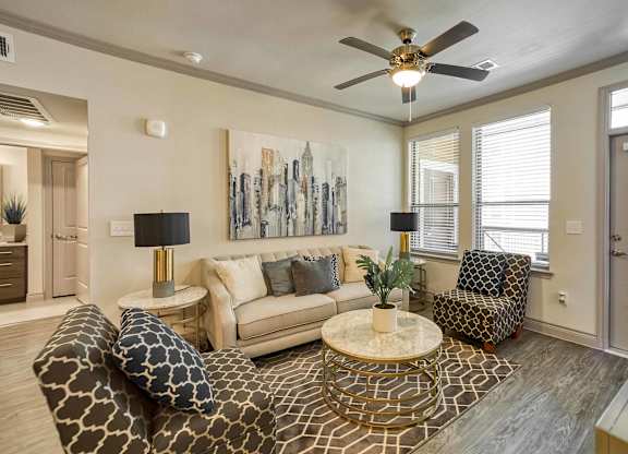 A living room with a patterned rug, a sofa, a chair, and a ceiling fan.