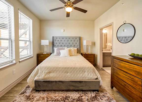 A bedroom with a large bed, a ceiling fan, and a rug on the floor.