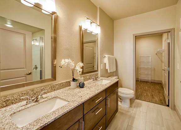 A bathroom with a sink, mirror, toilet, and shower.