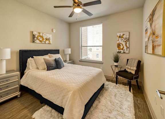 A bedroom with a bed, a chair, and a ceiling fan.