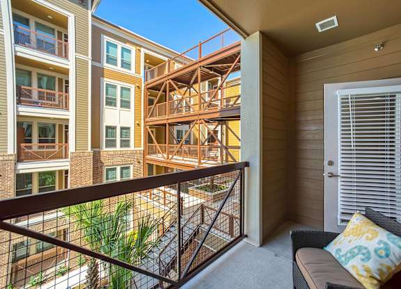A balcony with a cushioned chair and a pillow is overlooking a construction site.