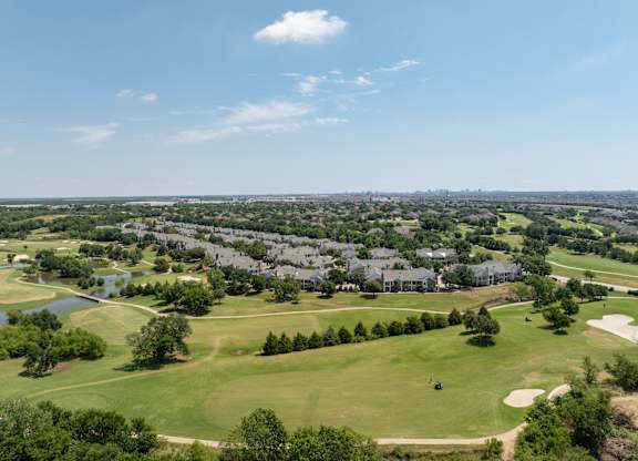 Wide aerial view of golf course fairways, ponds, and surrounding Carrollton neighborhood.