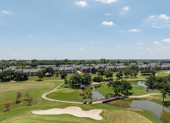 Aerial view of Coyote Ridge golf course, ponds, bridge, and nearby residences.