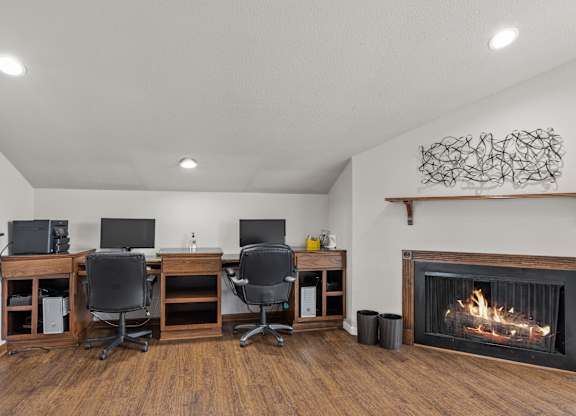 two computers and a fireplace in the corner of a room