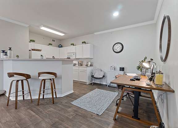 A kitchen with white cabinets and a bar area with stools.