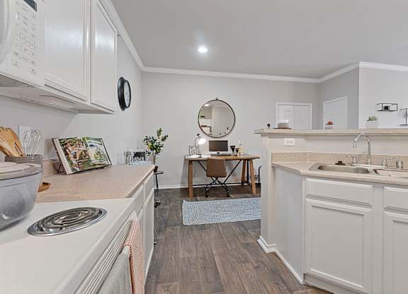 A kitchen with white cabinets and a wooden floor.