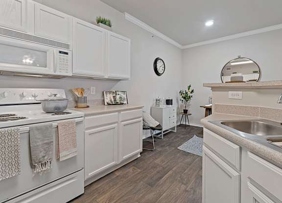 A kitchen with white cabinets and a wooden floor.