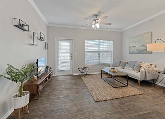 A living room with a white couch, a coffee table, and a ceiling fan.