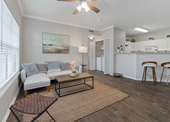 A living room with a white couch and a painting on the wall.