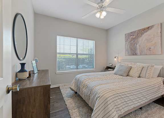 A bedroom with a large bed and a ceiling fan.