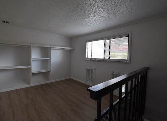 an empty living room with white shelves and a window