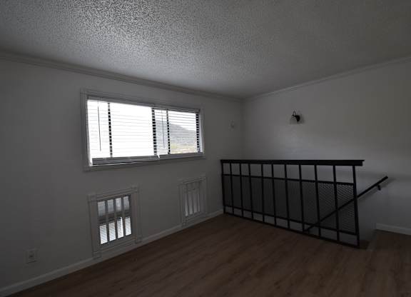 an empty living room with a staircase and a window