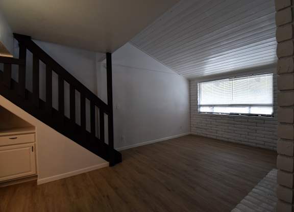 an empty living room with a staircase and a window