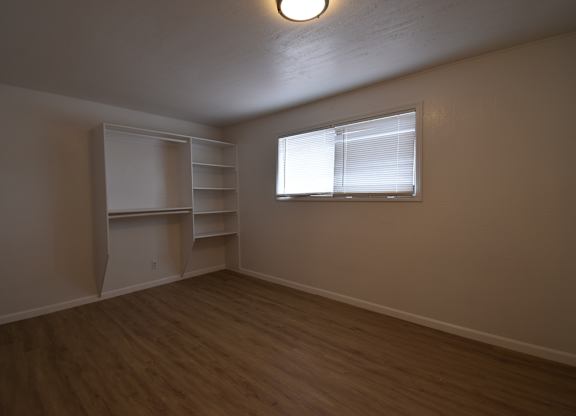 an empty living room with a window and shelves