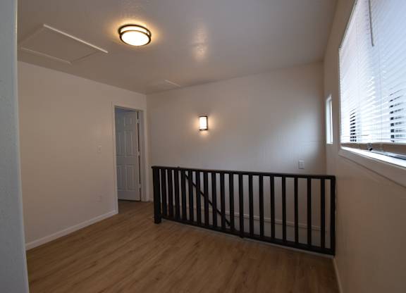 an empty living room with a railing and a window