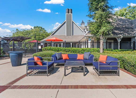 a patio with couches and a table in front of a house